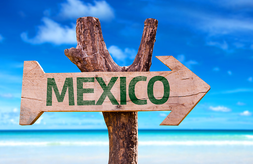 Mexico wooden sign with a beach on background