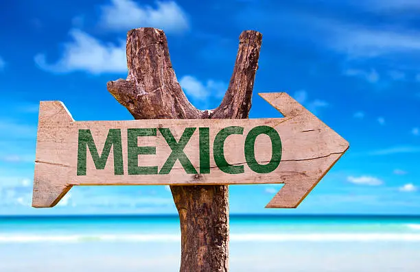 Photo of Mexico wooden sign with a beach on background