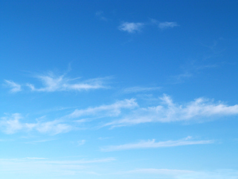 Soft wisps of airy clouds on a bright blue sky.