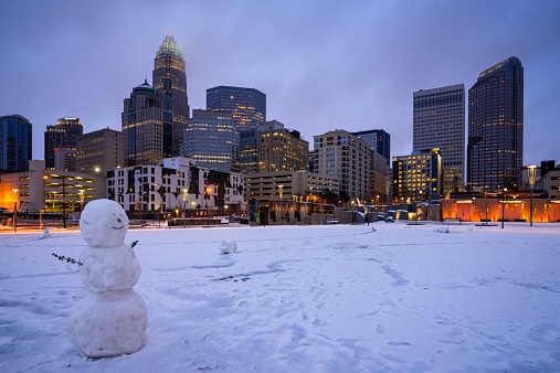 A snowy scene at Romare Bearden park in uptown Charlotte, North Carolina as a snowman sits in the foreground on a cold day.