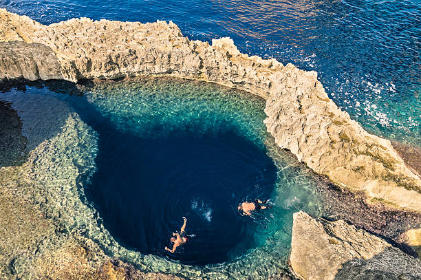 Blue hole at Azure Window in Gozo Malta Deep blue hole at the world famous Azure Window in Gozo island - Mediterranean nature wonder in the beautiful Malta - Unrecognizable scuba divers swimming to adventure water cave malta photos stock pictures, royalty-free photos & images