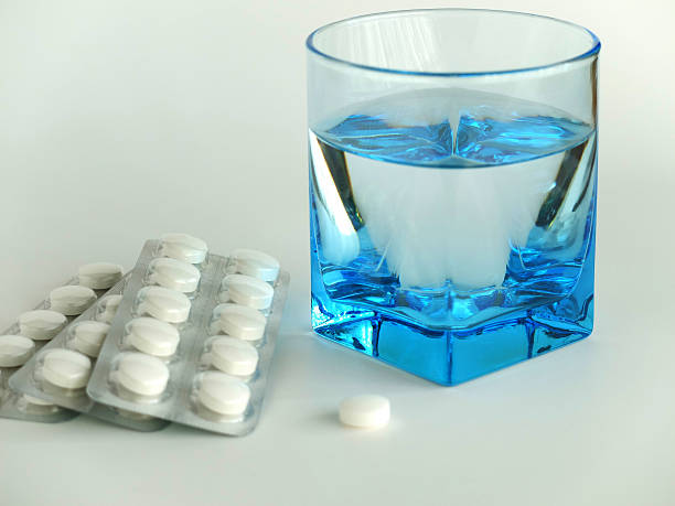 bolhas e uma cor branca de comprimidos com um copo de água. - painkiller vitamin pill full frame macro - fotografias e filmes do acervo