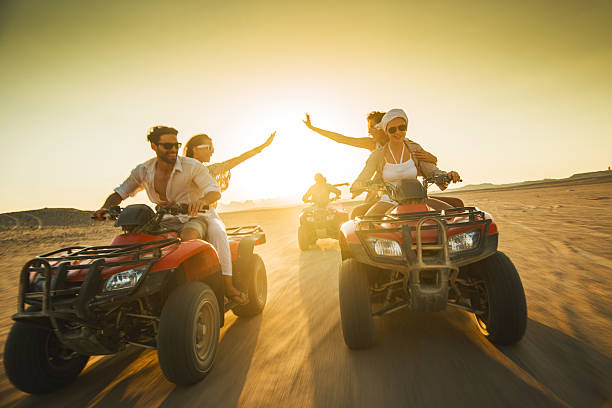 grupo grande de personas en automóvil feliz de cuatro con las bicicletas en el crepúsculo. - off road vehicle quadbike desert dirt road fotografías e imágenes de stock