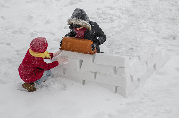 istock two sisters building a snow home 467554376