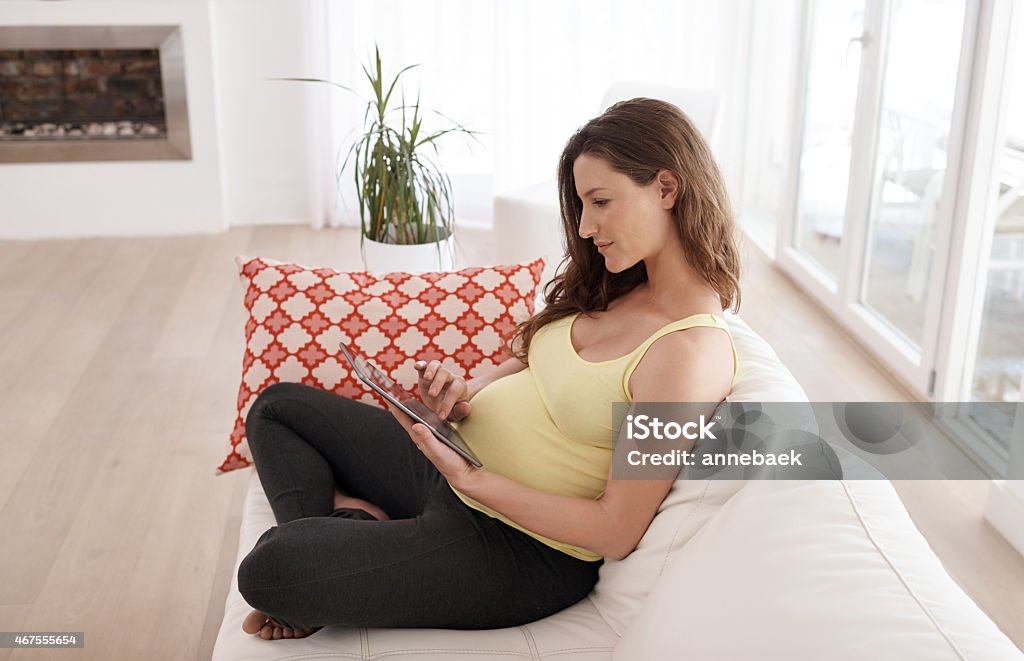 She's doing her research Shot of a young pregnant woman using her digital tablet while sitting on her living room sofahttp://195.154.178.81/DATA/istock_collage/a9/shoots/785357.jpg 2015 Stock Photo