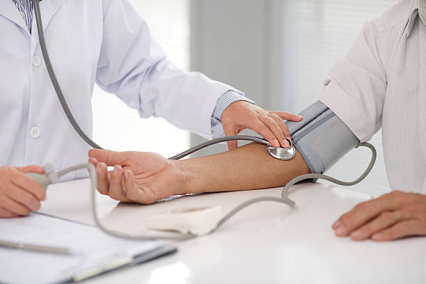 doctor checking patients blood pressure on right arm - huisarts druk stockfoto's en -beelden