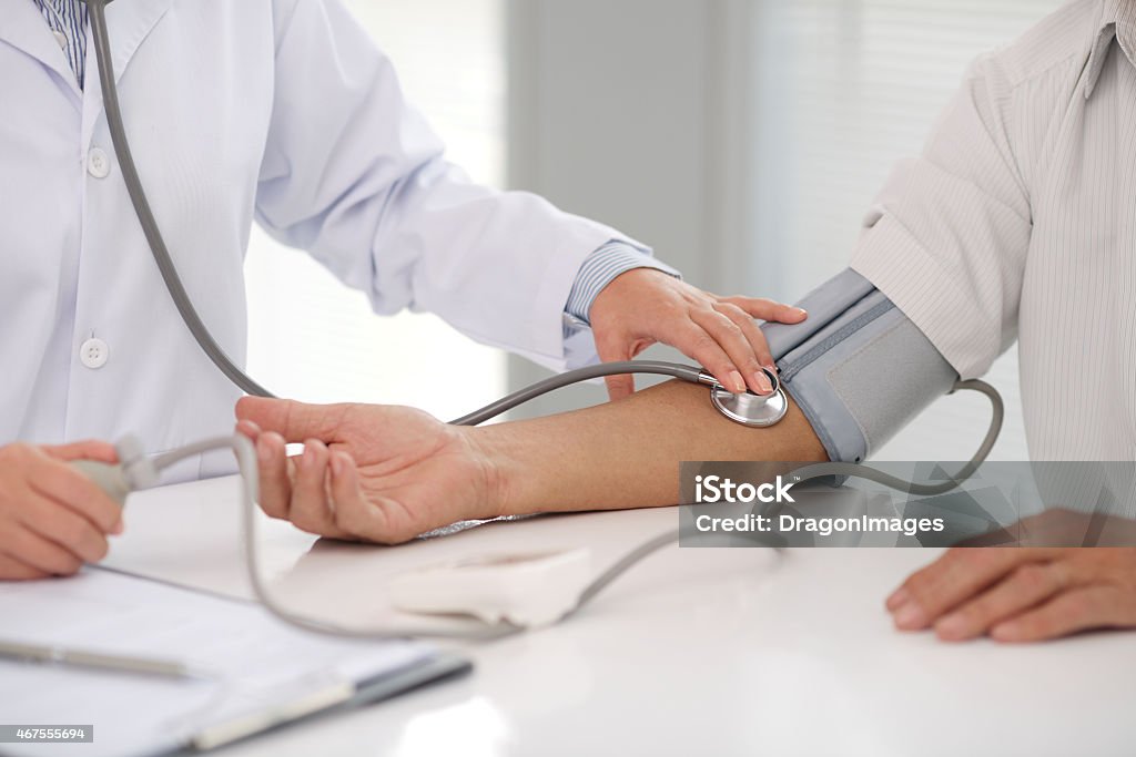 Doctor checking patients blood pressure on right arm Doctor checking blood pressure of the patient Blood Pressure Gauge Stock Photo