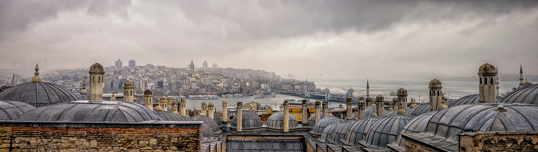 View over the Golden Horn and Bosphorus in Istanbul from the Fatih Mosque on a rainy cloudy day. The Galata Bridge (Galata Koprusu) is on the right of the panoramic photo. 
