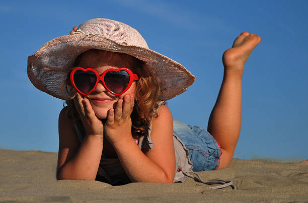 bela menina deitada em uma praia de areia - little girls fun lifestyle handcarves imagens e fotografias de stock