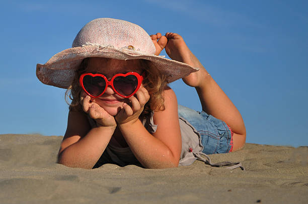 bela menina deitada em uma praia de areia - little girls fun lifestyle handcarves imagens e fotografias de stock