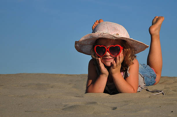 bela menina deitada em uma praia de areia - little girls fun lifestyle handcarves imagens e fotografias de stock