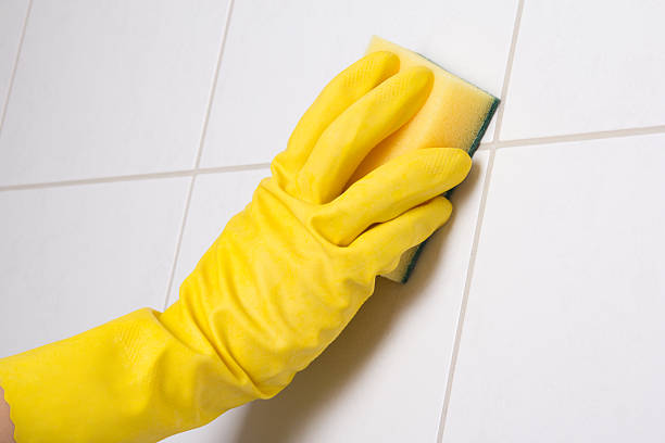 istock Hand in yellow glove cleaning tile wall 467581684