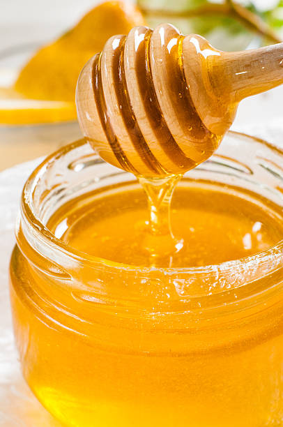 istock Honey jar with dipper and lemon flowing, wood background 467582480