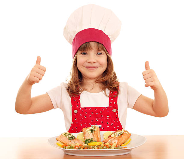 happy little girl cook with thumb up and salmon seafood stock photo