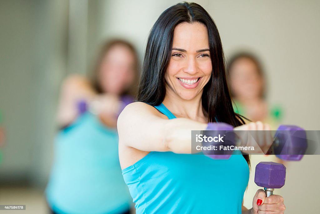 Female Fitness Class with Free Weights A group of female friends exercising with free weights in a health club, following an instructor. Exercise Class Stock Photo