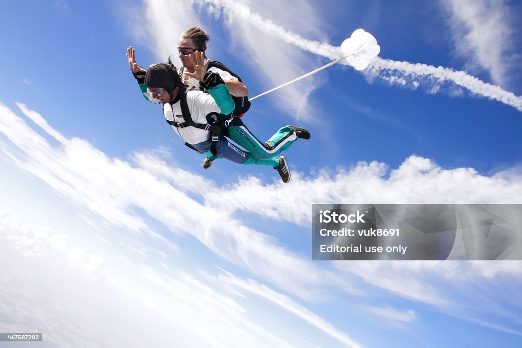 Tandem skydiving Rijeka, Сroatia - July 11, 2010: Tandem parachute instructor flying with a student who is firmly attached to him over the Rijeka airport Skydiving Stock Photo