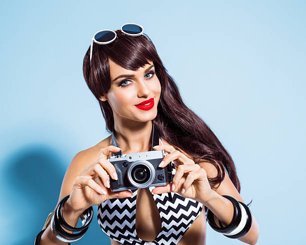 istock Smiling young woman wearing swimsuit taking picture using camera 467587870