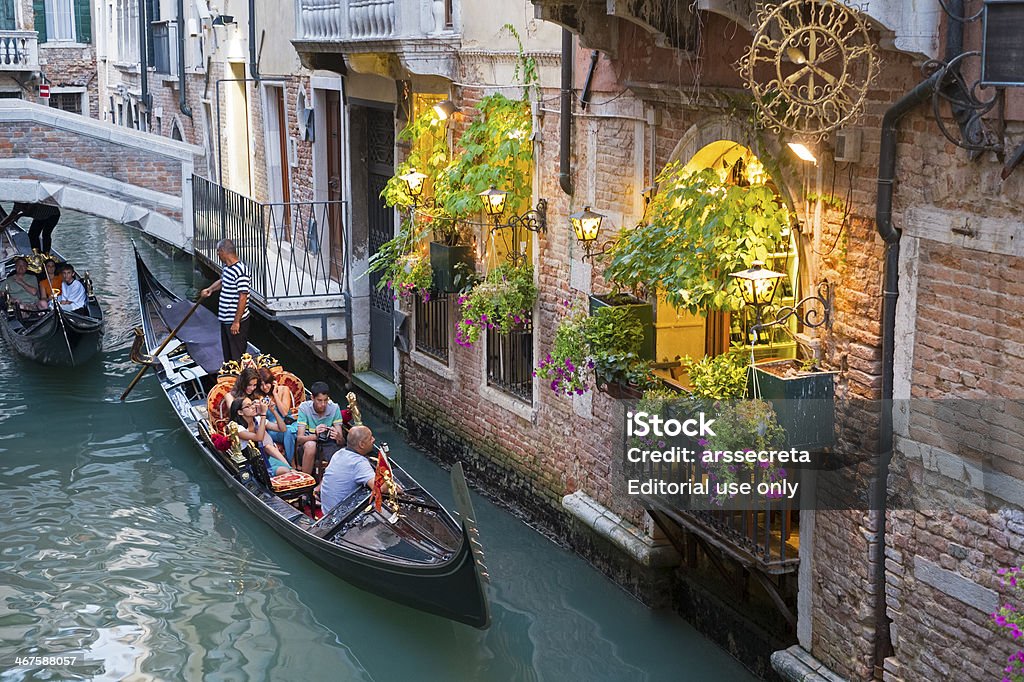 Tourists in a gondola Venice, Italy - July 18, 2012: A family rides a gondola in a typical canal at the italian city of the Veneto. Family Stock Photo