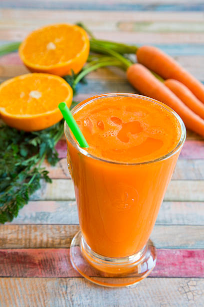 istock Orange carrot smoothie in glass on wood 467589152