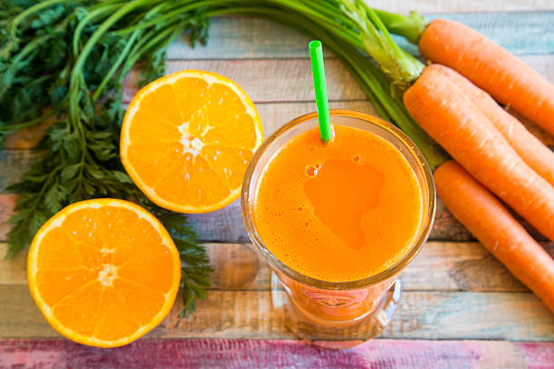 istock Orange carrot smoothie in glass on wood 467589154