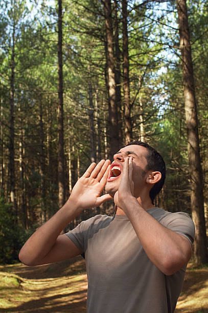 Young man standing alone in woods and yelling
