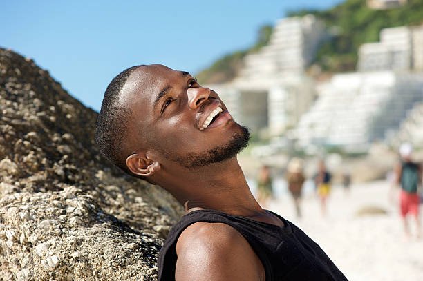 istock Friendly young man smiling at the beach 467595492