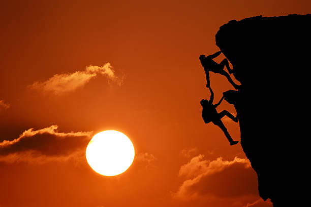 istock Silhouette of two men working together climbing mountain 467595952