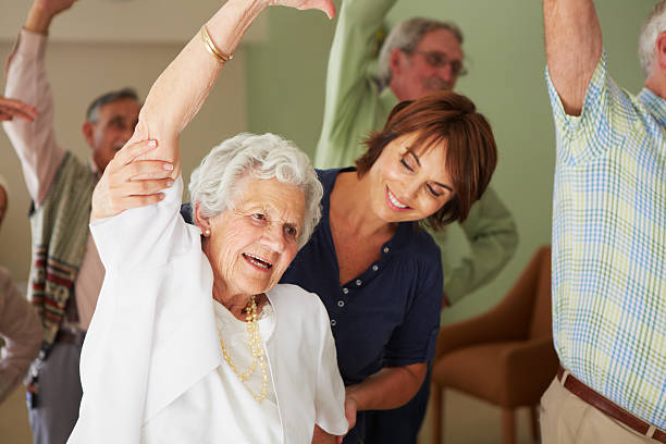 Assisting her in exercise Elderly lady recieving assistance from her exercise instructor young at heart stock pictures, royalty-free photos & images