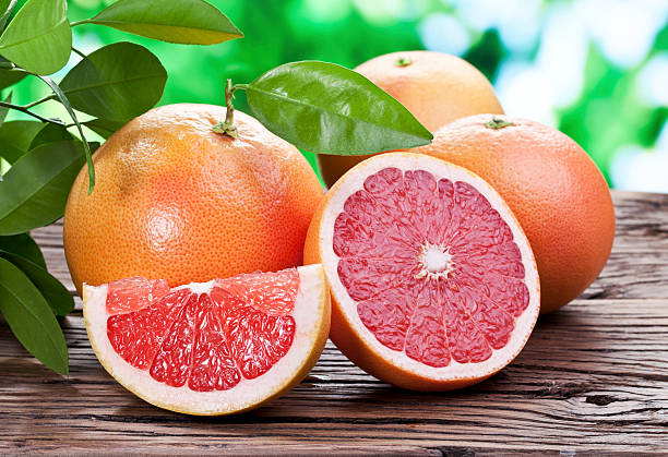 Grapefruits on a wooden table. Grapefruits on a wooden table with green foliage on the background. grapefruit photos stock pictures, royalty-free photos & images