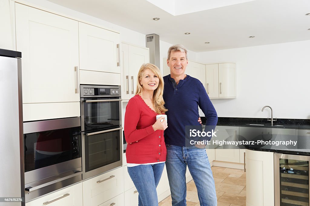 Pareja madura de pie en un hermoso equipada cocina juntos - Foto de stock de Cocina - Estructura de edificio libre de derechos