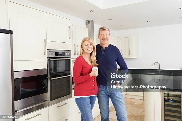 Pareja Madura De Pie En Un Hermoso Equipada Cocina Juntos Foto de stock y más banco de imágenes de Cocina - Estructura de edificio