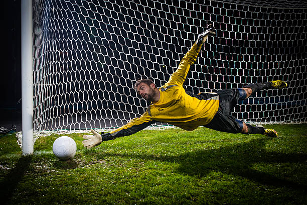 fußball torhüter springen auf ball - penalty soccer penalty shoot out goalie stock-fotos und bilder