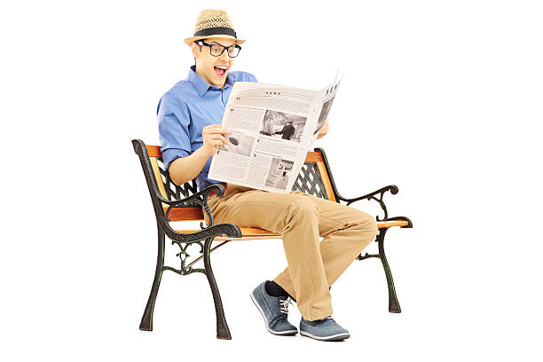 istock Surprised young man reading the news seated on a bench 467620427