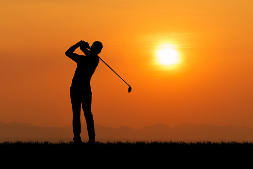 Silhouette of golfer against sunset