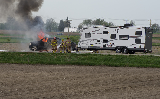 Atwood, Ontario, Canada - May 17, 2013: Fire fighters work to extingish the flames of a truck that started on fire while pulling a recreational vehicle travel trailer.