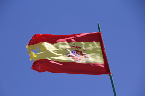 Spanish flag and a flag of Andalusia on the pole, waving in the wind in Málaga in Spain.