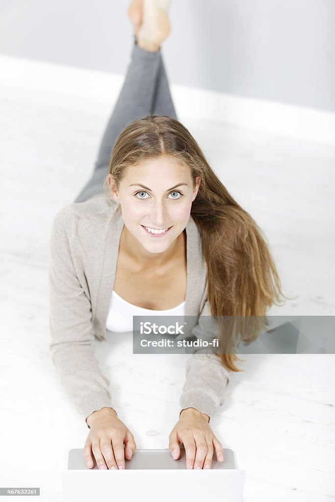 Woman working on a laptop Beautiful young woman working from home on her floor using a laptop Adult Stock Photo