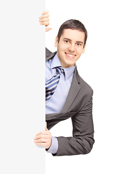 istock Young businessman in suit posing behind a blank panel 467633233