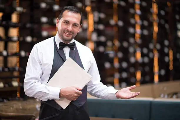 Friendly elegant waiter welcoming people to a restaurant