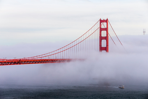 famous Golden Gate Bridge with low fog, a sightsee boat under the bridge, San Francisco, USA