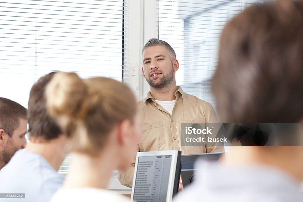 Adult education Group of adult students attending a job training. Focus on the male teacher standing in the background. 30-39 Years Stock Photo