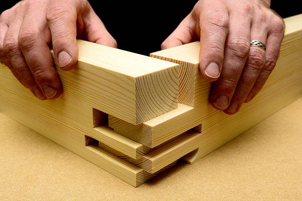 Woodworking Joint Detail Shown as an exploded view, a craft person uses their hands to pre assembles a comb joint in soft wood, pine stock prior to gluing and sanding. This double mortice and tenon joint helps the carpenter achieve maximum glueing area and increased strength.  labor intensive production line stock pictures, royalty-free photos & images