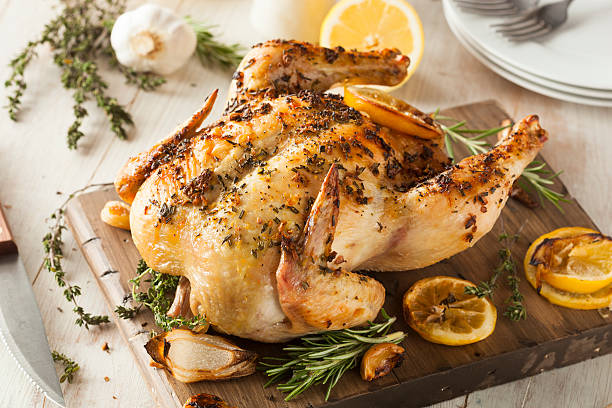 Homemade Lemon and Herb Whole Chicken Homemade Lemon and Herb Whole Chicken on a Cutting Board cooking with garlic stock pictures, royalty-free photos & images