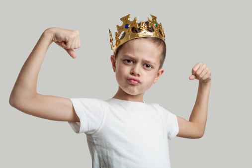 The little boy with a royal crown shows muscles.