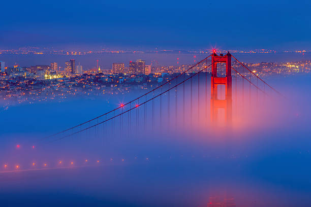 le golden gate bridge et la ville de san francisco avec brouillard basse - san francisco bay area golden gate bridge night bridge photos et images de collection