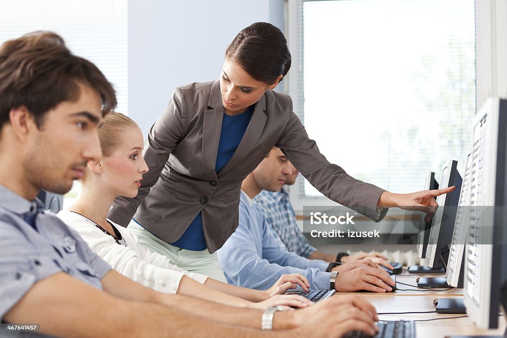 Computer course Group of adult students attending computer course. Focus on the female teacher pointing at computer screen. 30-39 Years Stock Photo