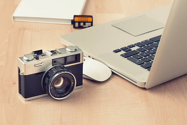 istock Vintage 35 millimeter camera next to open laptop and mouse 467643948