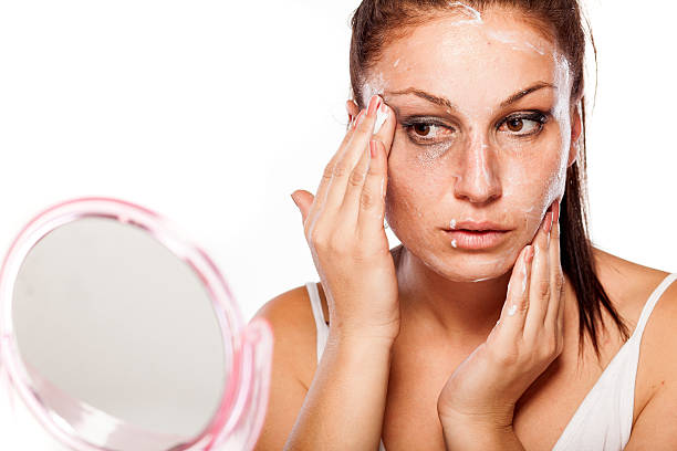 istock Young women applying cream to remove makeup from her face 467644336