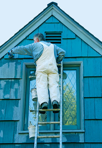 istock Man painting house's cedar shingles from ladder 467645277
