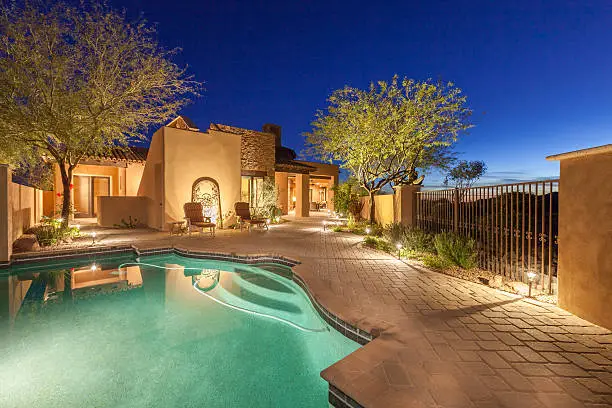 Luxury home backyard pool area in the evening.